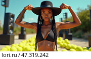 A fit woman stands confidently, flexing her biceps in a black bikini and hat amidst a vibrant display of tennis balls under a clear blue sky, radiating energy and strength. Tattooed female. Стоковое AI-изображение, AI-художник Sergey Grishin / Фотобанк Лори