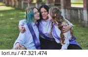 Three happy graduates hugging and celebrating their last school day, wearing purple sashes and bow ties. Стоковое фото, фотограф Mikhail Davidovich / Фотобанк Лори
