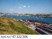 Vladivostok, Russia - August 9, 2021: Cargo cranes loading colorful containers in the port of vladivostok, russia, with the zolotoy rog bridge in the background. Редакционное фото, фотограф Mikhail Davidovich / Фотобанк Лори