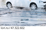 Fast white vehicle splashing water while driving through roadside puddle, dynamic wet surface motion capturing vehicle's speed and momentum. Стоковое фото, фотограф Mikhail Davidovich / Фотобанк Лори