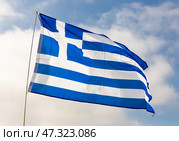 Against background of cloudy sky,white-blue flag of Greece flutters on flagpole. Стоковое фото, фотограф Яков Филимонов / Фотобанк Лори