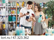 Couple buyer scans qr code on tile cleaner spay label. Стоковое фото, фотограф Яков Филимонов / Фотобанк Лори