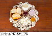 Top view of delicious country breakfast with white bread and fresh dairy products - cottage cheese, yogurt, milk on hand-knitted lace napkin on wooden table. Rustic still life. Flat lay, close-up, top view. Стоковое фото, фотограф Виктория Катьянова / Фотобанк Лори
