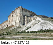 The majestic White Rock (Ak-Kaya), located in Crimea, near the town of Belogorsk. This is one of the most recognizable and picturesque natural wonders of the peninsula. Snow-white limestone cliffs rise above the steppe valley, creating a contrast between the bright blue sky, dry grasses and light rocks. The rock looks monumental, as if it keeps ancient secrets - it really has archaeological and historical significance.White Rock (Ak-Kaya) is a limestone cliff about 100 meters high, formed in the Cretaceous period. This is a place of archaeological finds, legends, filming and inspiration for artists and poets. Стоковое фото, фотограф Анна Кривицкая / Фотобанк Лори