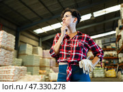 Thoughtful female storekeeper looking for tedious goods in building materials warehouse indoor. Стоковое фото, фотограф Яков Филимонов / Фотобанк Лори