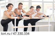 Female ballet student stretching at barre during group rehearsal. Стоковое фото, фотограф Яков Филимонов / Фотобанк Лори