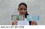 Venezuelan girl holds in her hands the money of her country and the American dollar. Inflation concept. Стоковое видео, видеограф Mikhail Davidovich / Фотобанк Лори