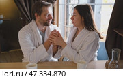 Mature couple in a white bathrobes hugging each other kissing at home room. Intimate Moment. Tender embrace shared between a loving middle age man and woman, husband and wife. Deep love. Vacation. Стоковое видео, видеограф Марина Демидюк / Фотобанк Лори