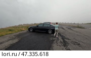 Перевал Зустен в Швейцарских Альпах. Женщина возвращается к автомобилю на стоянке. Июль. Susten Pass in the Swiss Alps. The woman returns to the car in the parking lot. July. Редакционное видео, видеограф Горшков Александр / Фотобанк Лори
