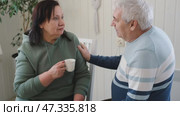 Old couple have breakfast sitting at the kitchen table, drink coffee. Embracing elderly man and woman. Senior couple together marriage in retirement talking with each other. Enjoying the pleasantries. Стоковое видео, видеограф Марина Демидюк / Фотобанк Лори