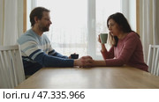 Loving mature couple interactions at home. Husband and wife hugging, holding hands and drinking morning coffee together. Man and woman talk about plans for weekend. Natural lighting. Intimate moments. Стоковое видео, видеограф Марина Демидюк / Фотобанк Лори