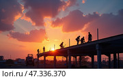 Silhouetted workers collaborate on a construction project as the sun sets, casting a warm glow through fluffy clouds on the horizon. Стоковое AI-изображение, AI-художник Sergey Grishin / Фотобанк Лори