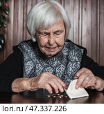 Portrait of an old woman counting money. The concept of old age, poverty, austerity. Стоковое фото, фотограф Matej Kastelic / Фотобанк Лори