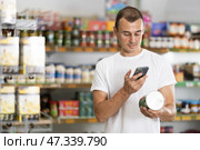 Man in supermarket scan QR code on jar canned food. Стоковое фото, фотограф Яков Филимонов / Фотобанк Лори