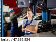 Female car service worker keeps records of work performed by auto mechanics in car service station - makes notes on paper. Стоковое фото, фотограф Яков Филимонов / Фотобанк Лори