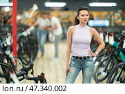 Avid female cyclist exploring variety of bicycles in store. Стоковое фото, фотограф Яков Филимонов / Фотобанк Лори