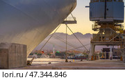 Hurghada, Egypt - Mar 12 2023, a panoramic view of the port with cranes and piece of bow of the cruise ship on foreground, at evening, Hurghada, Egypt. Стоковое фото, фотограф Сергей Богомяко / Фотобанк Лори