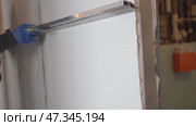 Leveling the plaster on the wall using a metal rule. The builder plasters the wall in the apartment with cement mortar. Стоковое видео, видеограф Darya Komarova / Фотобанк Лори