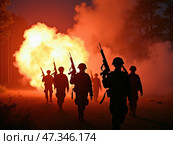 A group of soldiers advances through dense smoke and flames during a military training exercise at night, demonstrating teamwork and readiness in challenging conditions. Стоковое AI-изображение, AI-художник Sergey Grishin / Фотобанк Лори