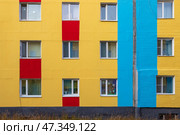 Фасад красочного разноцветного здания. Стена здания окрашена в желтый, синий и красный цвета. Окна многоквартирного дома. Вид снаружи на жилой дом. Окрашенное панельное здание. Посёлок Палатка, Магаданская область, Россия. Стоковое фото, фотограф Андрей Степанов / Фотобанк Лори