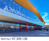Международный аэропорт Магадан (Сокол) имени В. С. Высоцкого, Магаданская область, Россия. Вид снаружи на современное здание терминала аэропорта Магадан (новый терминал открыт в декабре 2024 года). Над входом в аэровокзальный комплекс вывеска на русском языке «Аэропорт Магадан». Около здания пассажиры с чемоданами. Развитие авиационной транспортной инфраструктуры на Дальнем Востоке России. Редакционное фото, фотограф Андрей Степанов / Фотобанк Лори