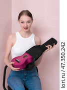 Attractive young female musician is taking ukulele out of black soft case and looking at camera. Стоковое фото, фотограф А. А. Пирагис / Фотобанк Лори
