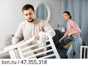 Guy rubbing wooden furniture while wife vacuuming sofa. Стоковое фото, фотограф Яков Филимонов / Фотобанк Лори
