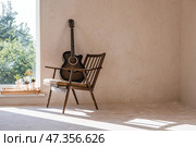 Guitar. Guitar chords. Acoustic guitar. Music. Musical background. An image of an acoustic guitar in a room with a retro armchair. Hard light. Shadows. Стоковое фото, фотограф Photojuli / Фотобанк Лори