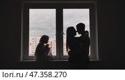 Silhouette of lovers with children on the background of windows from a new apartment. Стоковое видео, видеограф Mikhail Davidovich / Фотобанк Лори