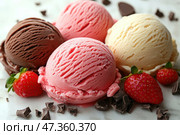 A delicious assortment of ice cream balls: strawberry, vanilla and chocolate. They are laid out on a light surface, surrounded by fresh strawberries and pieces of dark chocolate. The texture of the ice cream is detailed - frozen crystals and soft curves are visible. The colors are rich and saturated, conveying a feeling of freshness and sweetness. The composition looks very tasty and aesthetically pleasing - ideal for advertising desserts or a culinary blog. Стоковое AI-изображение, AI-художник Анна Кривицкая / Фотобанк Лори