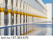 Abu Dhabi, United Arab Emirates - Jan 10 2024, panoramic view of Sheikh Zayed Grand Mosque colonnade with arches and pool on foreground, at daytime, Abu Dhabi, United Arab Emirates. Редакционное фото, фотограф Сергей Богомяко / Фотобанк Лори