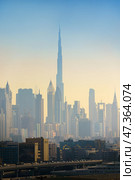 Dubai, United Arab Emirates - Jan 20 2024, panoramic skyline view of Dubai city downtown with skyscrapers, Burj Khalifa tower in center, in early morning in smoke and smog, Dubai, United Arab Emirates. Стоковое фото, фотограф Сергей Богомяко / Фотобанк Лори