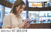 A girl in a shopping mall dials a message on the phone. Стоковое видео, видеограф Mikhail Davidovich / Фотобанк Лори