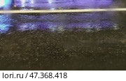 Night city street. It's raining late in the evening, puddles have formed on the road. The black asphalt is wet from the rain. Cars drive through the puddles, splashing muddy water. Стоковое видео, видеограф Andrew_Swarga / Фотобанк Лори
