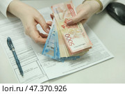 Девушка держит в руках российские рубли на фоне договора займа. Стоковое фото, фотограф Ольга Зиновская / Фотобанк Лори