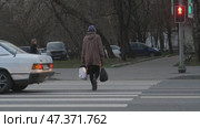 Женщина стоит по середине дороги, мимо проезжают машины. Переход через дорогу на красный сигнал светофора. Нарушение правил дорожного движения. Редакционное видео, видеограф Семён Прудий / Фотобанк Лори