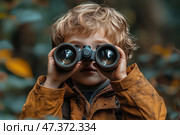 A small boy with light brown curly hair, dressed in a warm autumn jacket of ochre color. He looks attentively through binoculars, holding them with both hands. The background is blurred, but the outlines of the forest are discernible - dense foliage, muted green and yellow-orange shades. The boy looks fascinated and a little surprised - as if he saw something interesting in the distance for the first time. Стоковое AI-изображение, AI-художник Анна Кривицкая / Фотобанк Лори