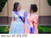Jubilant graduates wearing colorful sashes hugging, commemorating academic success and shared bond of friendship. Стоковое фото, фотограф Mikhail Davidovich / Фотобанк Лори