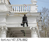 Рабочий-маляр спускается на верёвке  с террасы  по стене дома. Стоковое фото, фотограф Snezka / Фотобанк Лори
