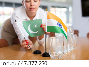 Unrecognizable girl sets midget flags of India and Pakistan before international negotiations. Стоковое фото, фотограф Яков Филимонов / Фотобанк Лори