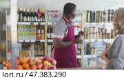 African man store clerk serves woman customer, sells something and shows product. Стоковое видео, видеограф Яков Филимонов / Фотобанк Лори