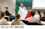 Adult female teacher showing students the flag of Italy. Стоковое видео, видеограф Яков Филимонов / Фотобанк Лори