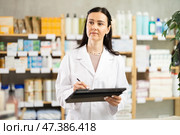 Middle-aged female pharmacist restocking with tablet in drugstore. Стоковое фото, фотограф Яков Филимонов / Фотобанк Лори