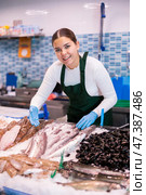 Positive seller woman demonstrating lucet in fish store. Стоковое фото, фотограф Яков Филимонов / Фотобанк Лори