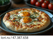 A delicious Adjarian khachapuri, a traditional Georgian dish. It is an open flatbread made of fluffy dough, filled with melted cheese and two brightly colored egg yolks. The edges of the flatbread are browned, and the dish is sprinkled with fresh herbs, probably parsley or cilantro. In the background, fresh cherry tomatoes and herbs are blurred in a bowl, creating a warm and cozy atmosphere. Стоковое AI-изображение, AI-художник Анна Кривицкая / Фотобанк Лори