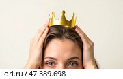 Young woman holding golden crown on head, self confident girl with arrogant expression, concept of pride, vanity, ego, superiority, narcissism, self importance, success, ambition. Стоковое AI-изображение, AI-художник Павел Муравьев / Фотобанк Лори