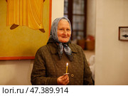 Belarus, Gomel city, celebrating the church holiday of Easter in St. Nicholas Monastery 01.05. 2016 year. Unknown grandmother in church.Grandmother in church with a candle.Believing grandmother. Редакционное фото, фотограф Лазаренко Светлана / Фотобанк Лори