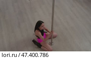 Attractive young woman performs dance on pole, then descends to floor, where she continues to move in a graceful and sensual manner. Стоковое видео, видеограф Strunov David / Фотобанк Лори