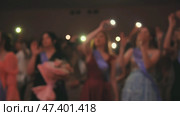 Graduates waving flashlights during commencement ceremony, celebrating their academic achievement with flowers and sashes. Стоковое фото, фотограф Mikhail Davidovich / Фотобанк Лори