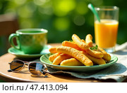 Outdoor table with cheese sticks, a green coffee cup, sunglasses, and orange juice in sunlight, capturing a casual breakfast scene. Ideal for portraying relaxed mornings. Стоковое AI-изображение, AI-художник Анна Маркина / Фотобанк Лори